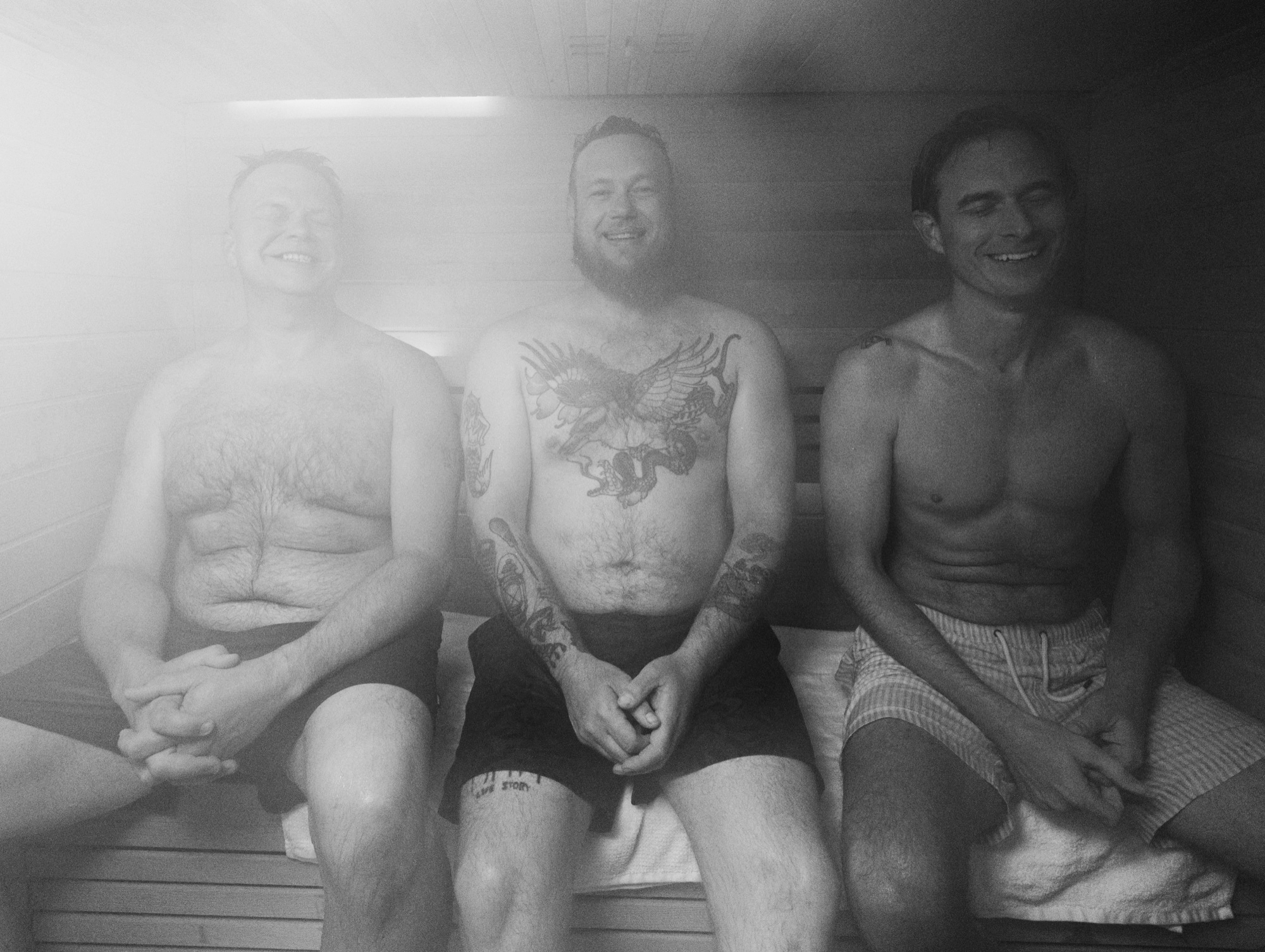 Three men sitting together in a sauna, laughing